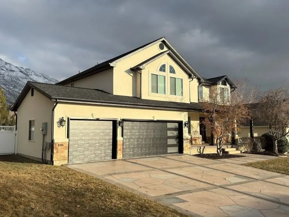 A large yellow house with two garage doors and a driveway.