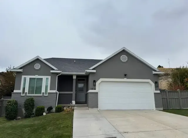 A gray house with a white garage door is for sale.