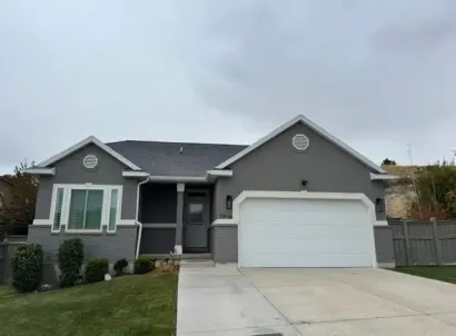 A gray house with a white garage door is for sale.