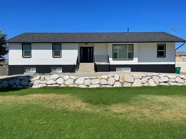 A white and black house with a stone wall in front of it.