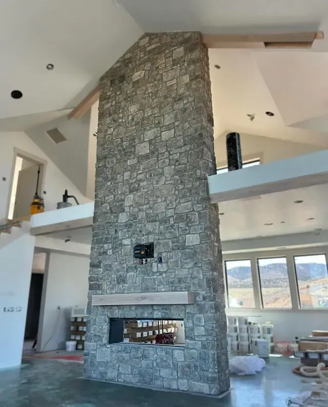 A large stone fireplace is in the middle of a living room.