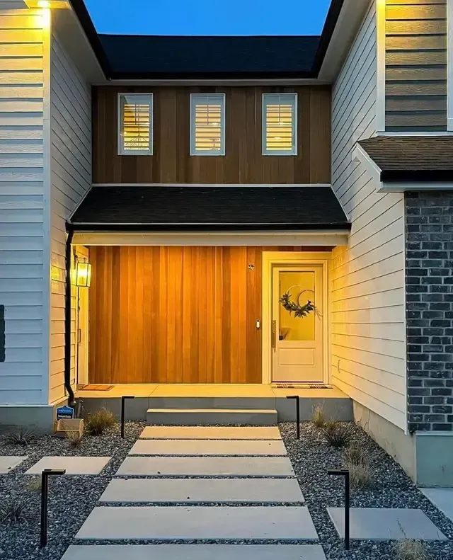 The front of a house with a wooden door and a walkway leading to it.