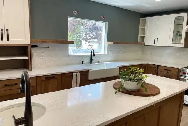 A kitchen with wooden cabinets , white counter tops , a sink and a window.