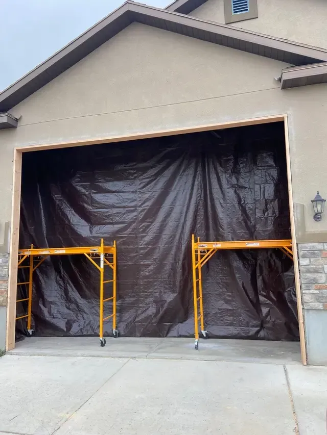 A large garage door is covered with a brown tarp