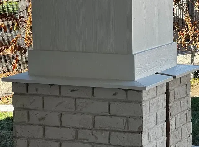 A white brick column is sitting on top of a white brick base.