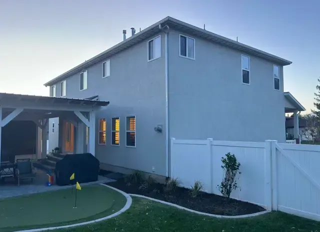 A large house with a white fence and a putting green in front of it.