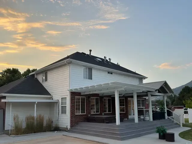 A large white house with a pergola on the front of it.