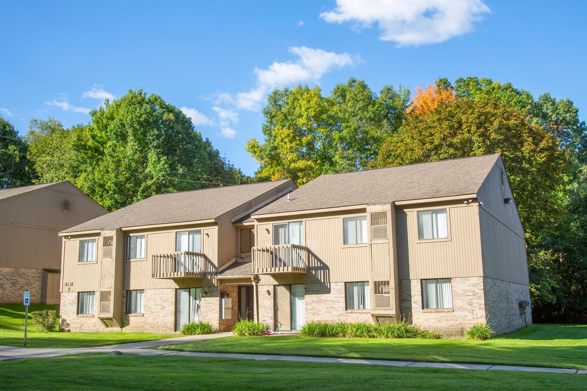 A large apartment building with a lot of windows and trees in the background.