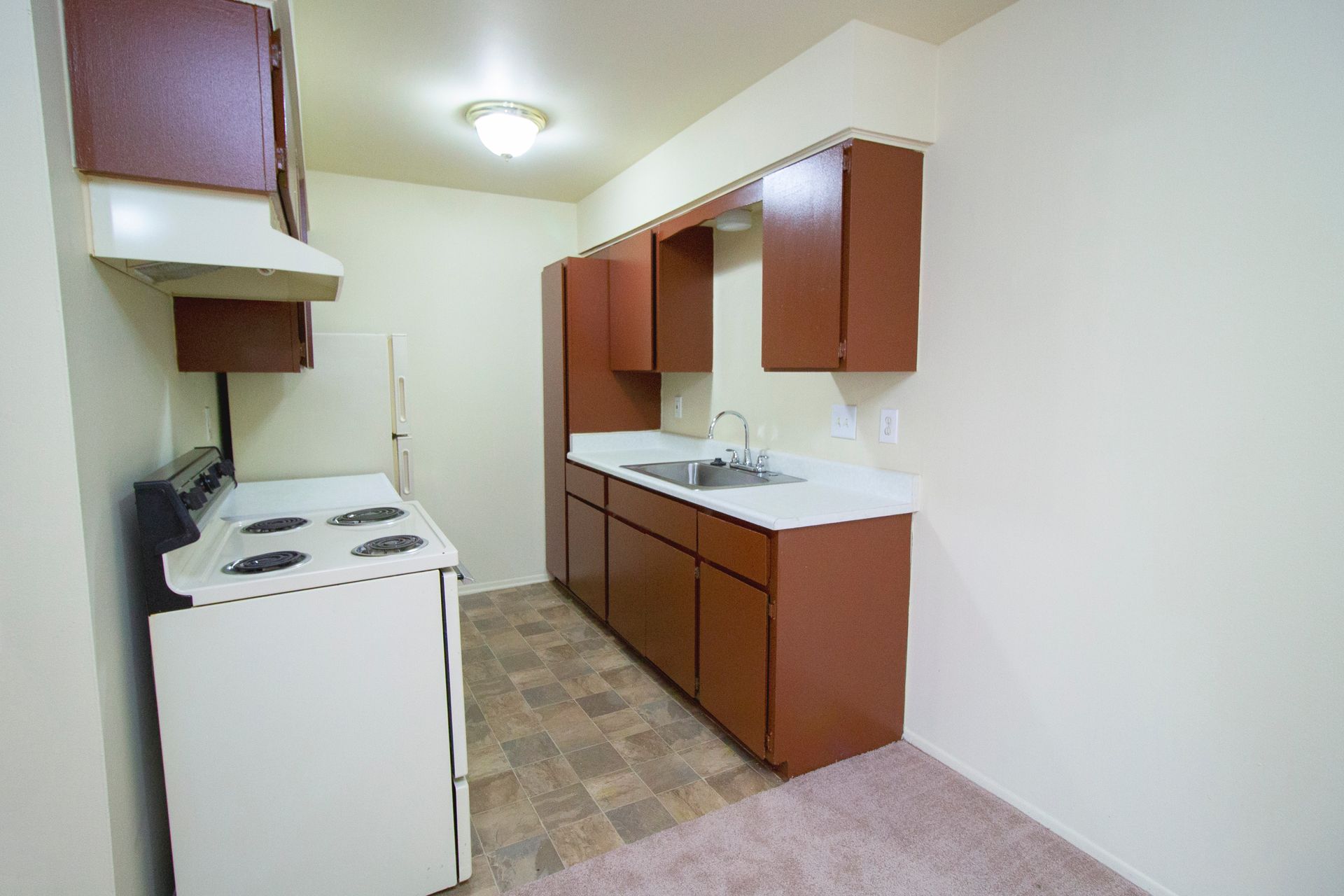 A kitchen with a stove , refrigerator , sink and cabinets
