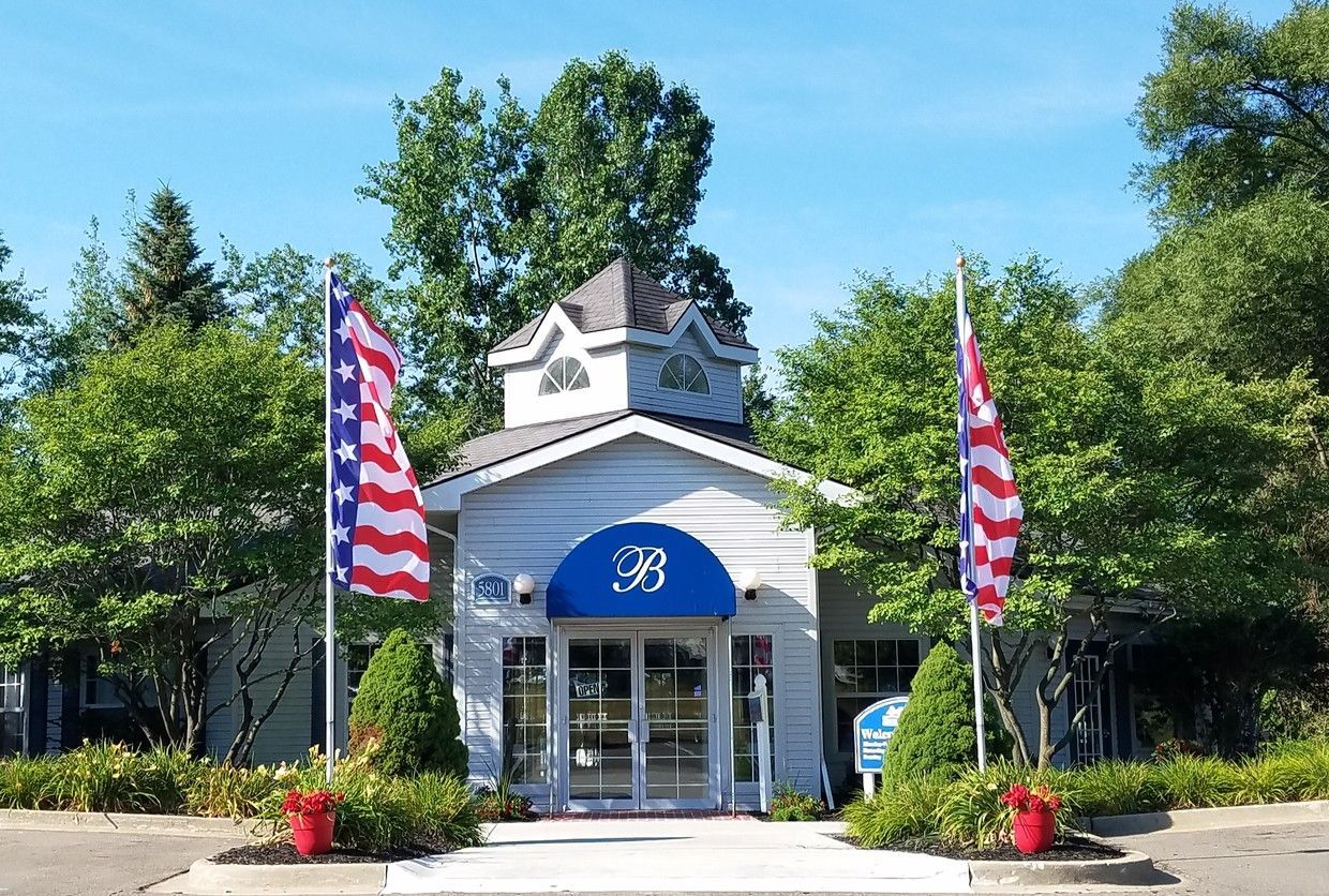 A white building with a blue awning and american flags in front of it.