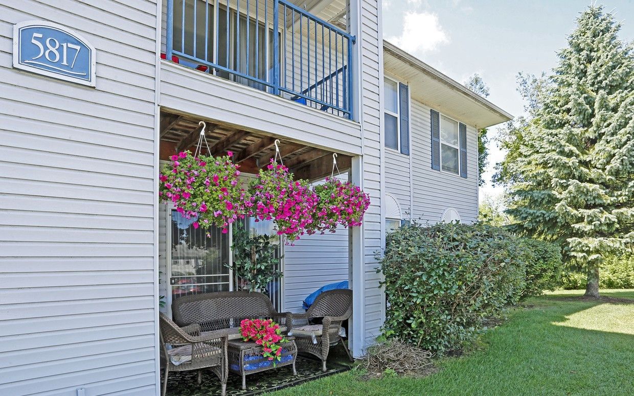 A white house with a balcony and flowers on the porch.