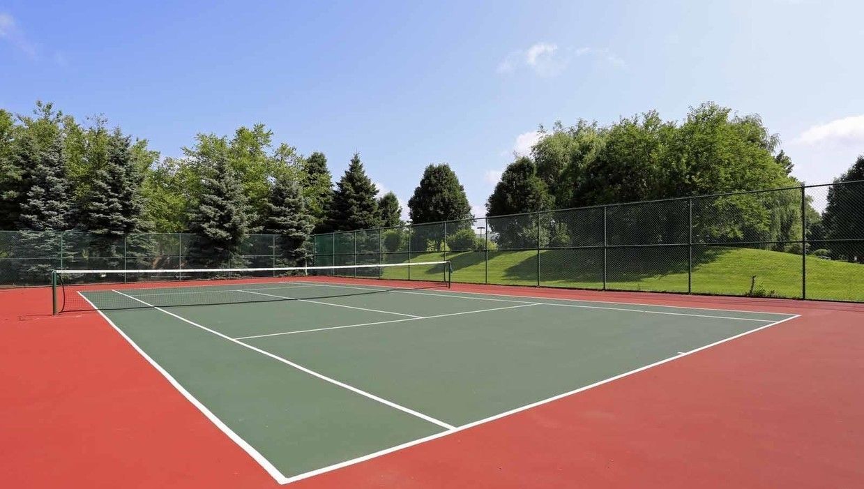 A tennis court with trees in the background and a blue sky