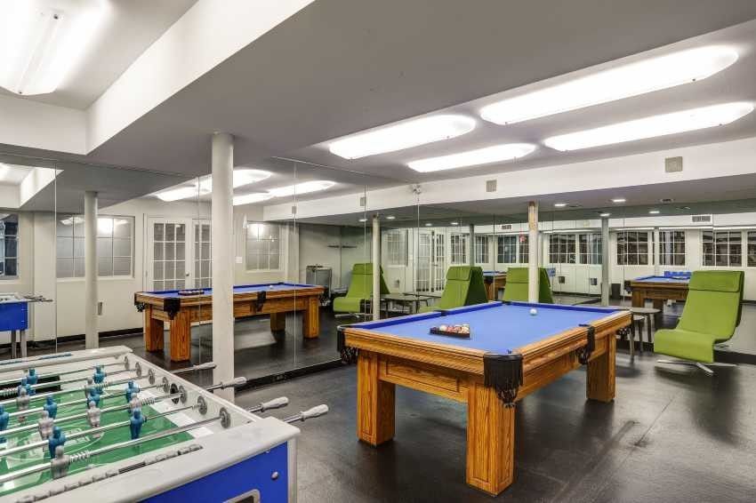 A pool table and a foosball table are in a game room.