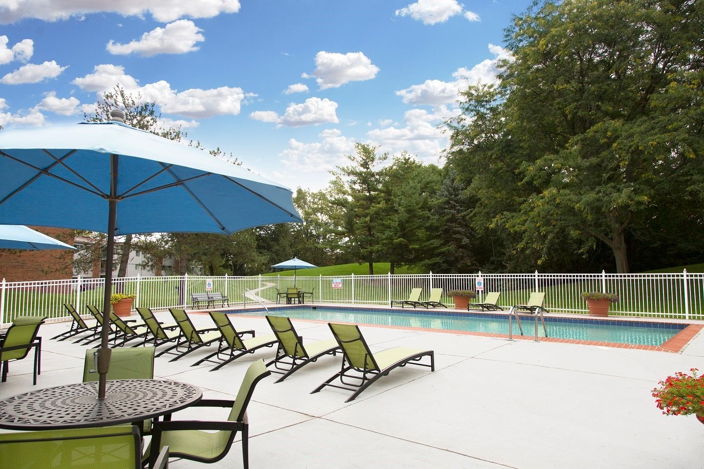 A swimming pool with a table and chairs under an umbrella