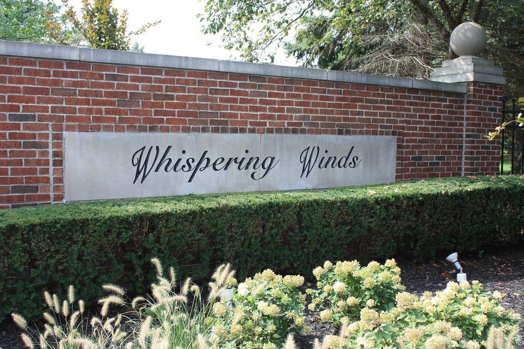 A brick wall with a sign that says whispering winds