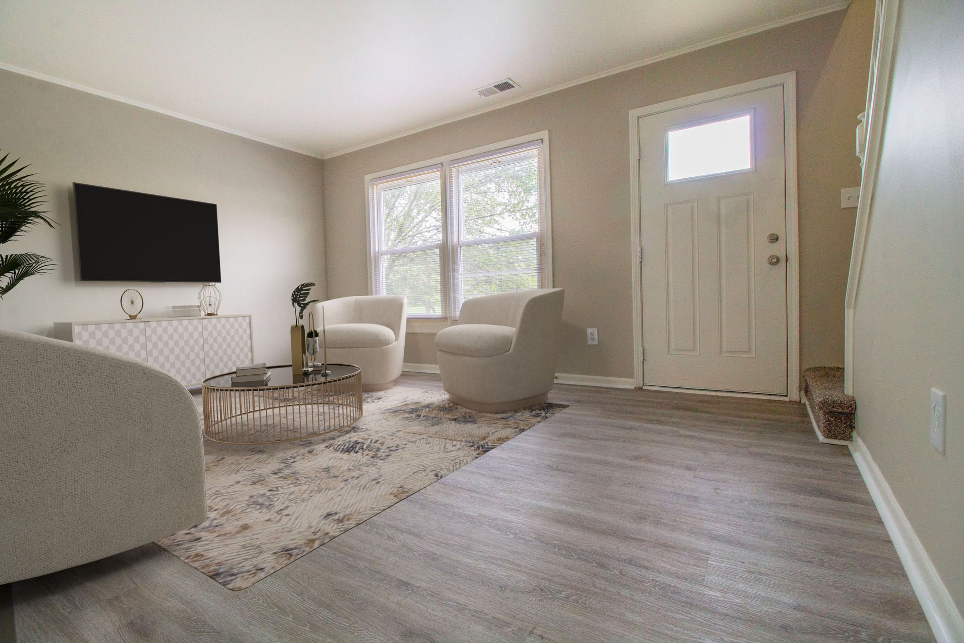 A living room with two chairs , a coffee table , and a flat screen tv.