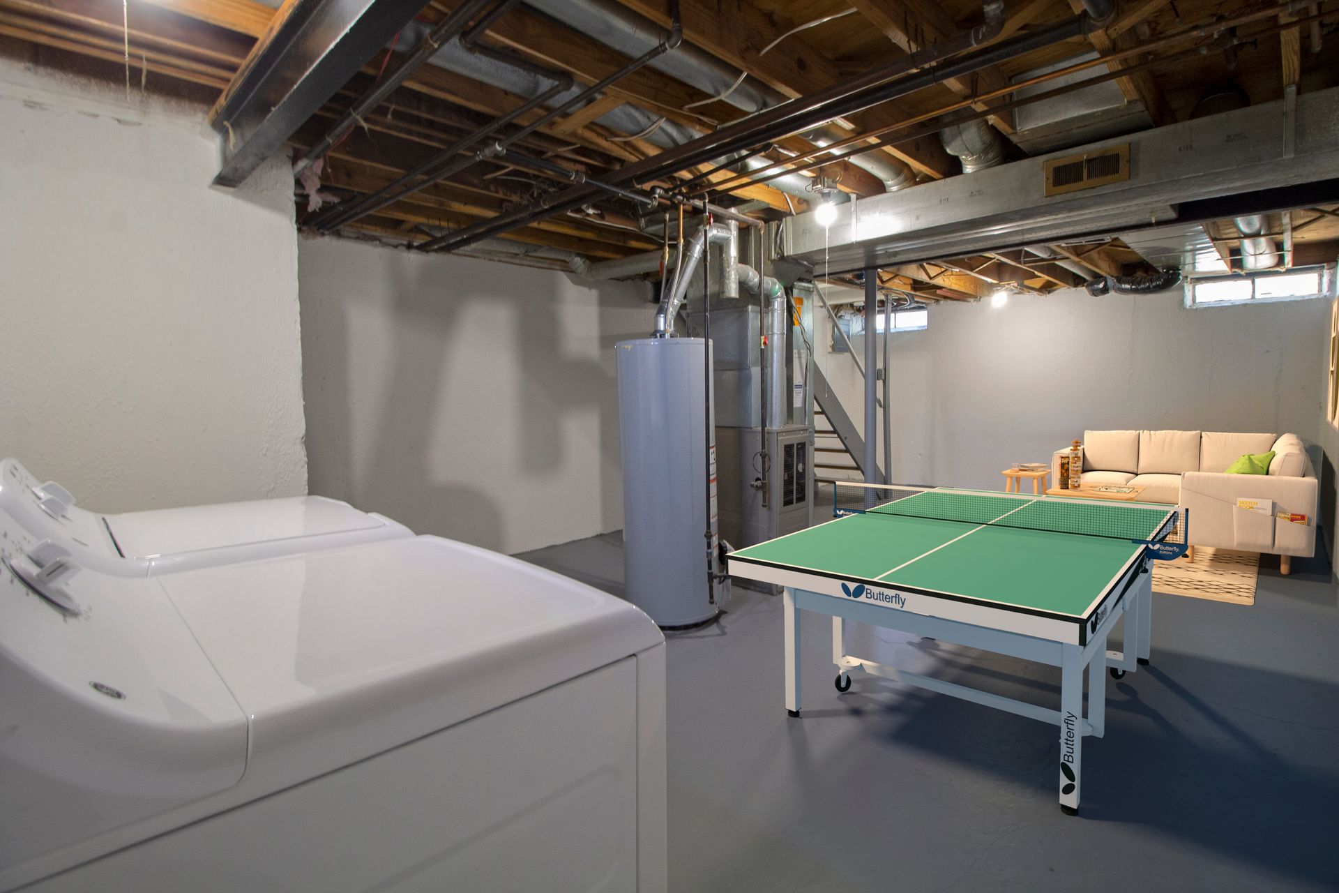 A basement with a ping pong table and a washer and dryer.