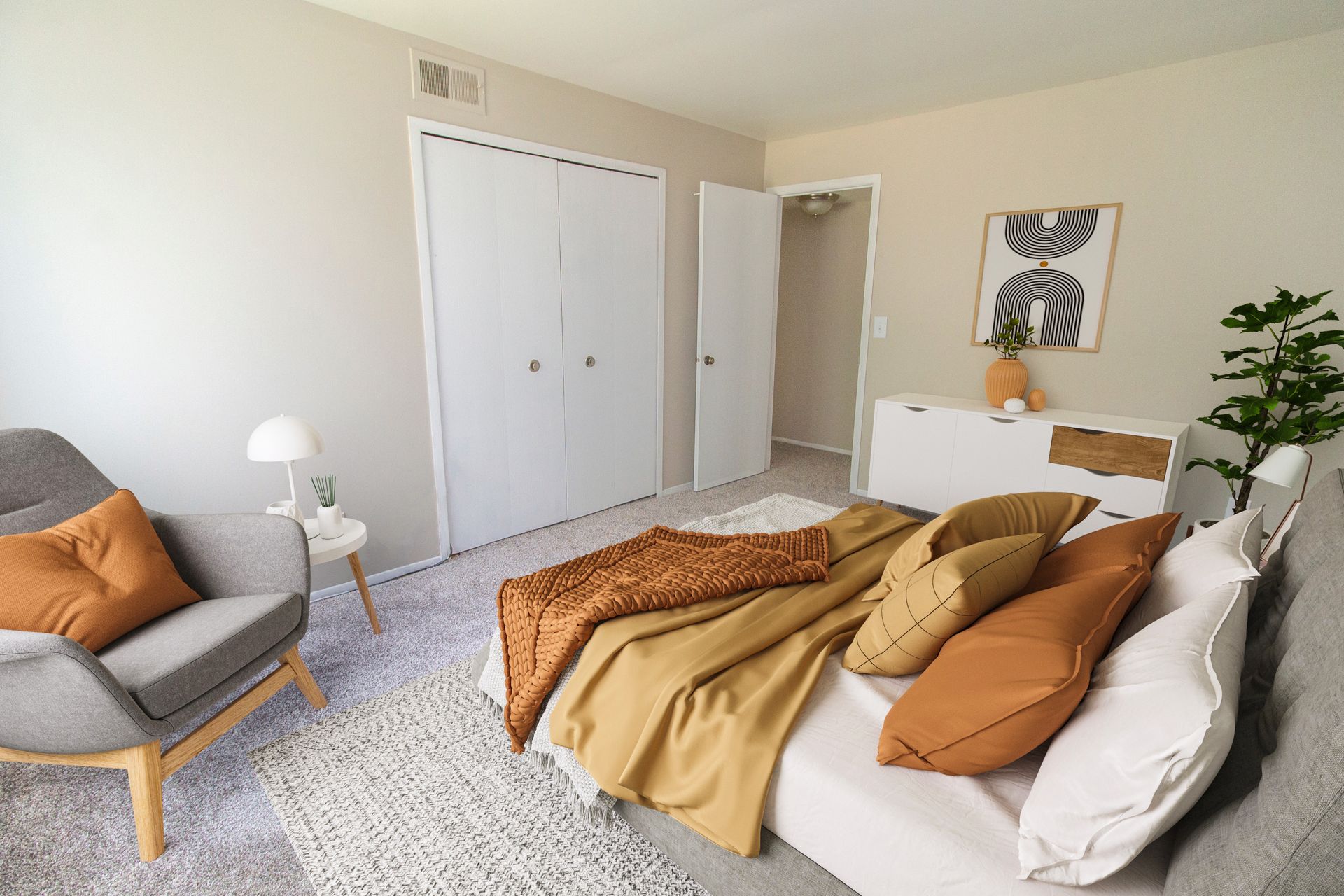 A bedroom with a bed , chair , dresser and closet.