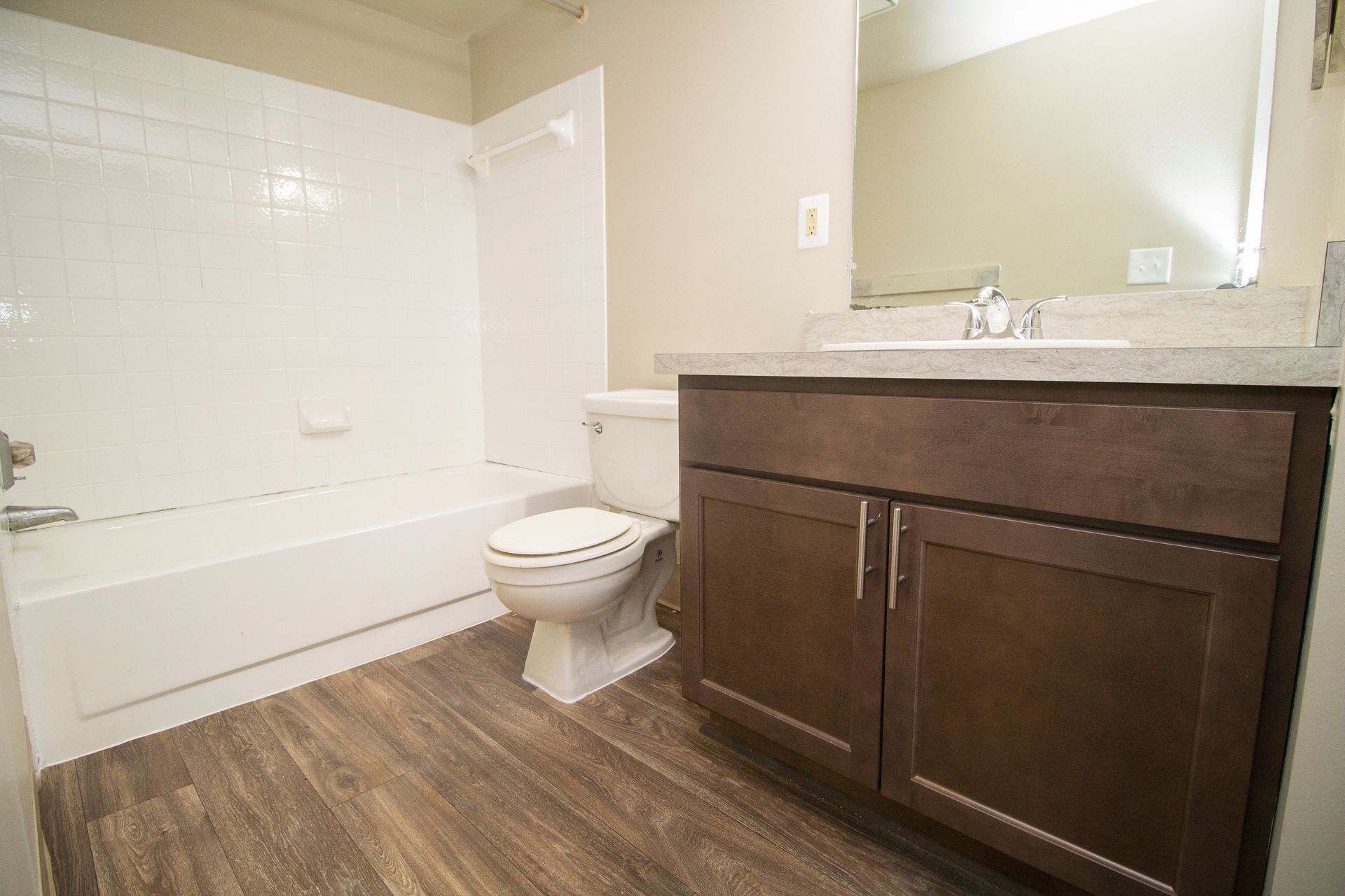 A bathroom with a toilet , sink , bathtub and mirror.