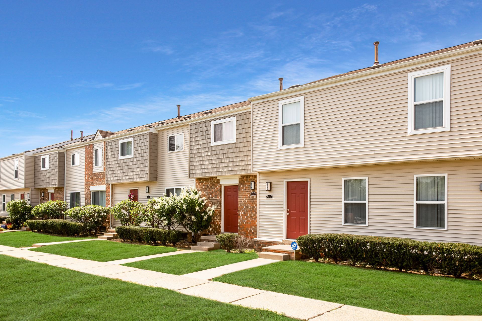 A row of apartment buildings with a lush green lawn in front of them.