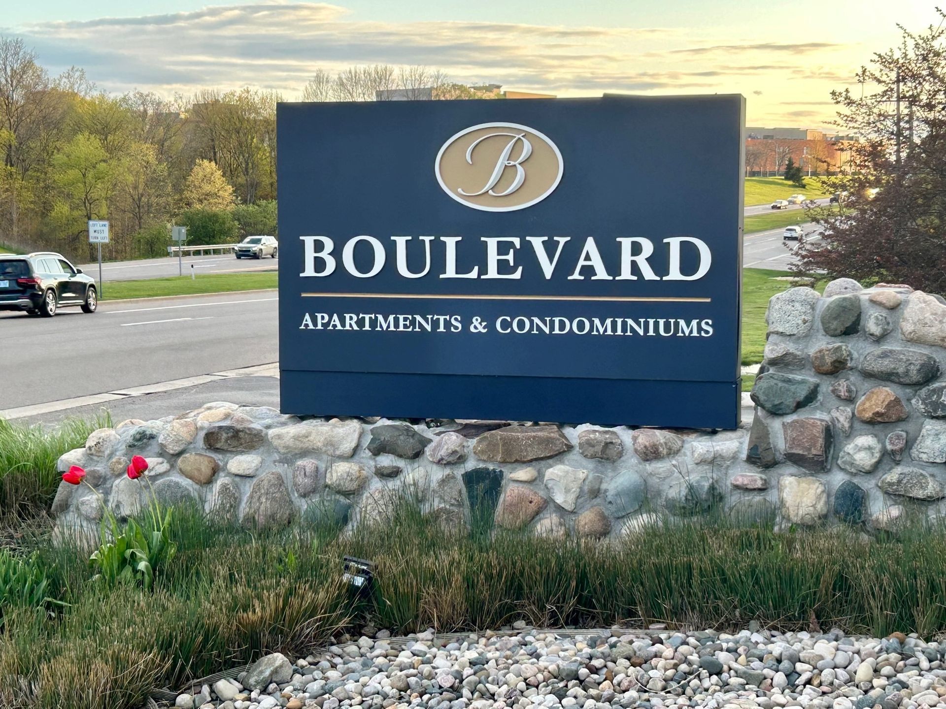 A sign for boulevard apartments and condominiums is sitting on top of a stone wall.