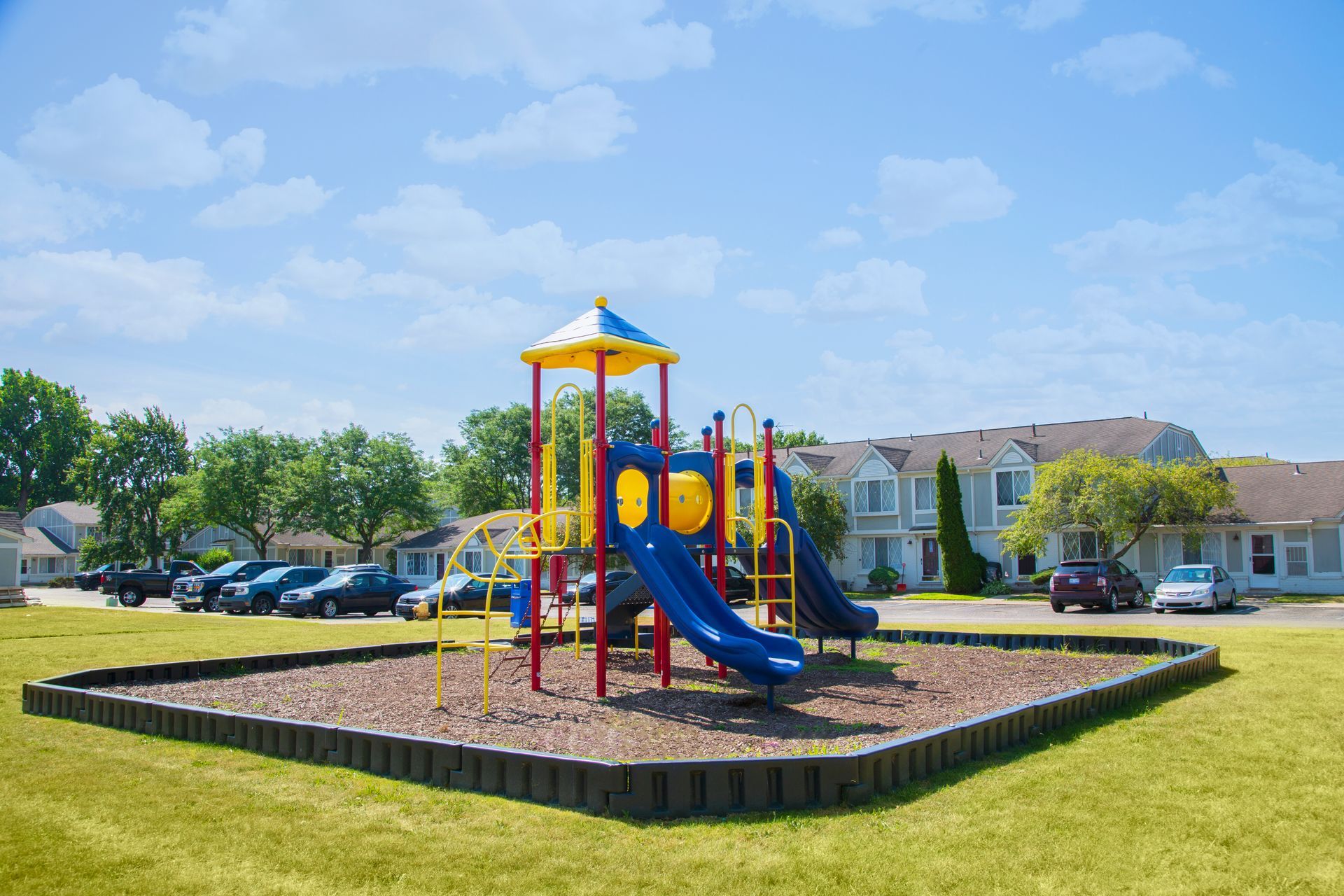 A colorful playground is sitting in the middle of a lush green field.