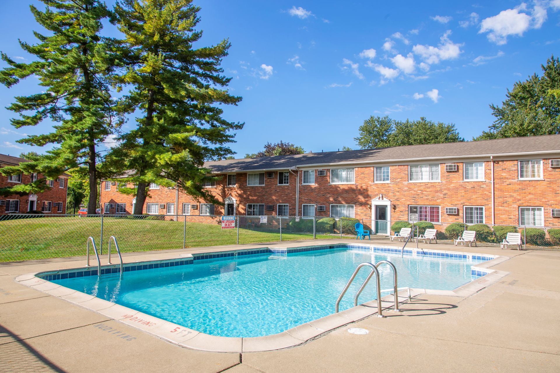 A large swimming pool is in front of a brick building.