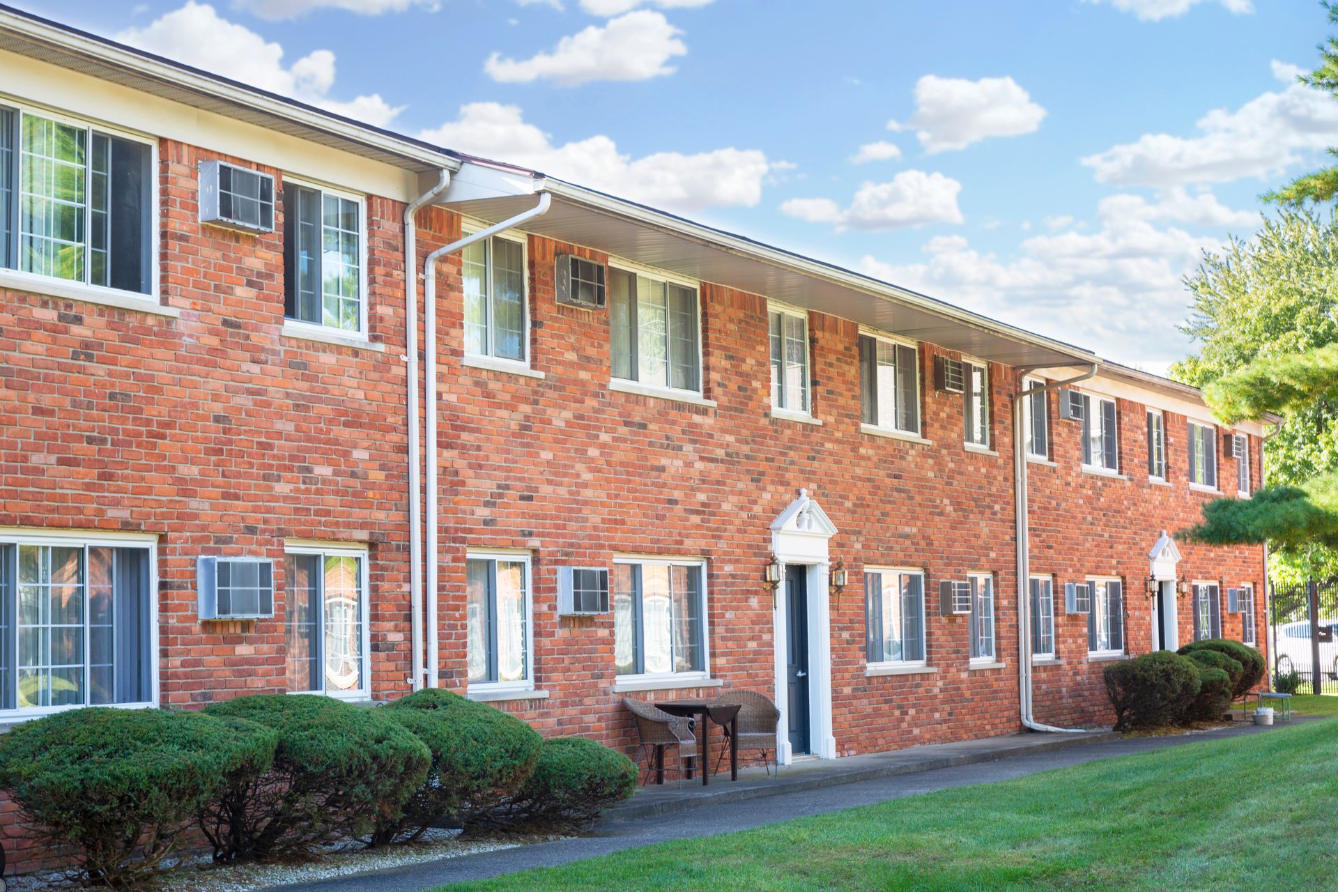 A brick apartment building with a lot of windows and a lawn in front of it.