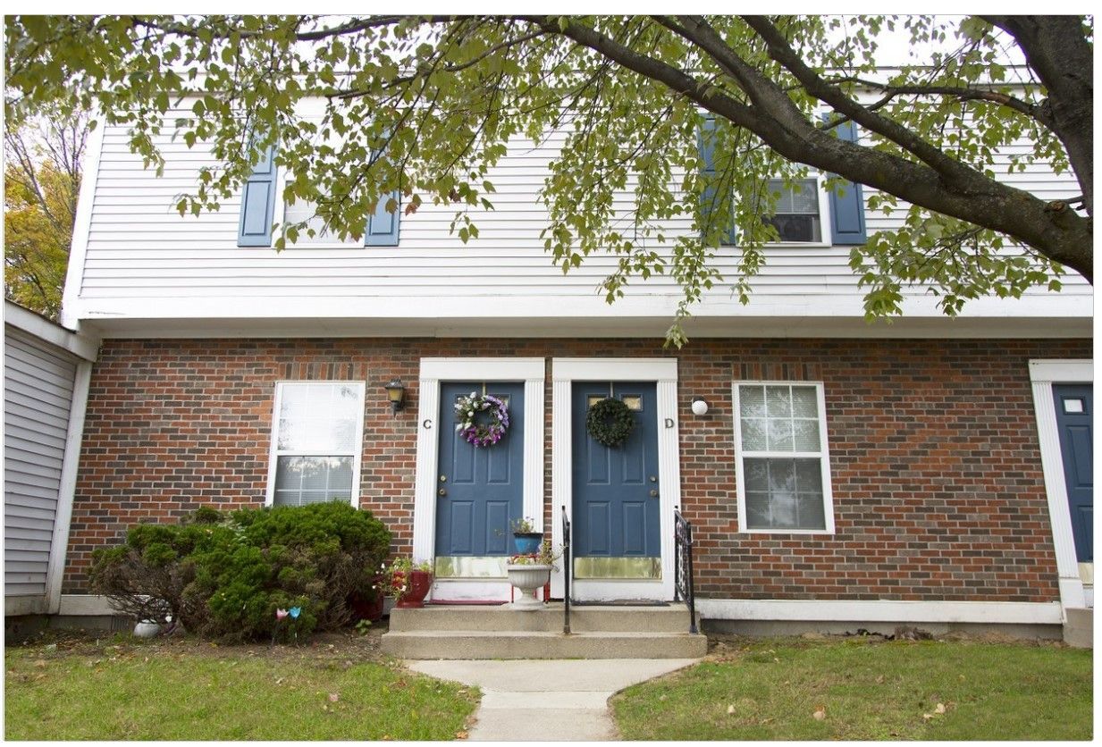 A brick house with blue doors and white siding