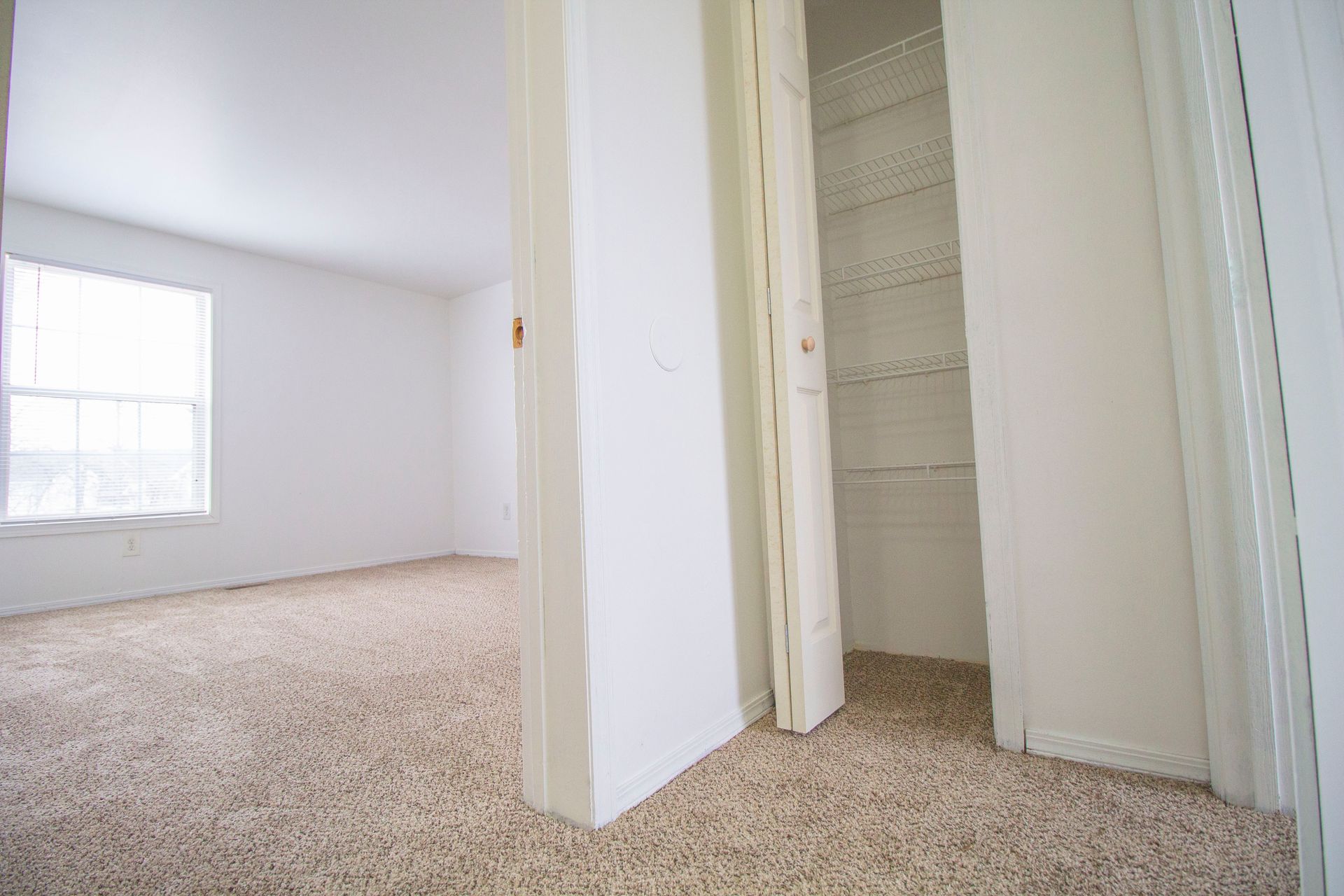 An empty room with a closet and a window.