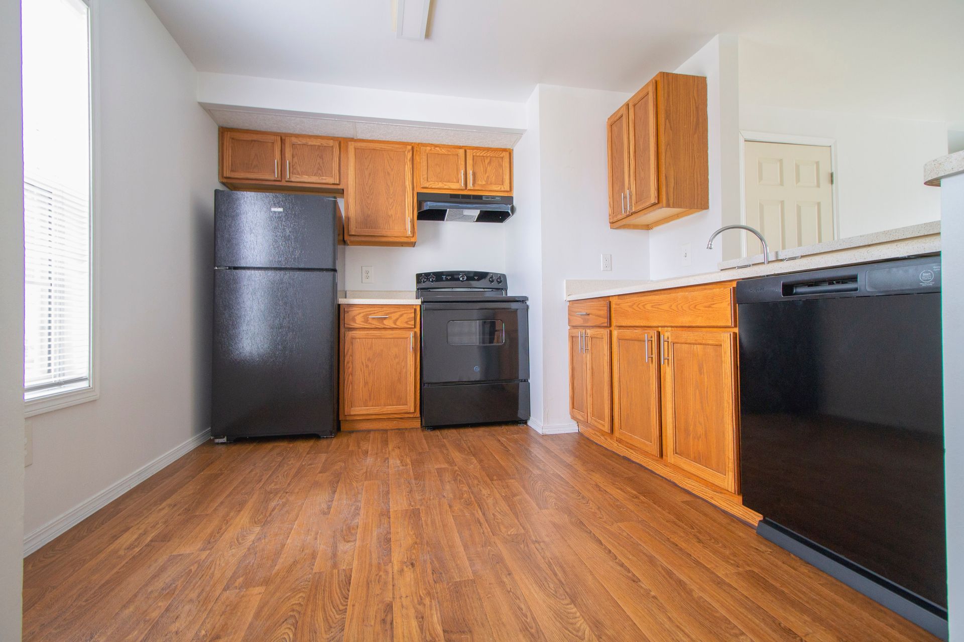 A kitchen with wooden cabinets , a black refrigerator , a black stove , and a black dishwasher.