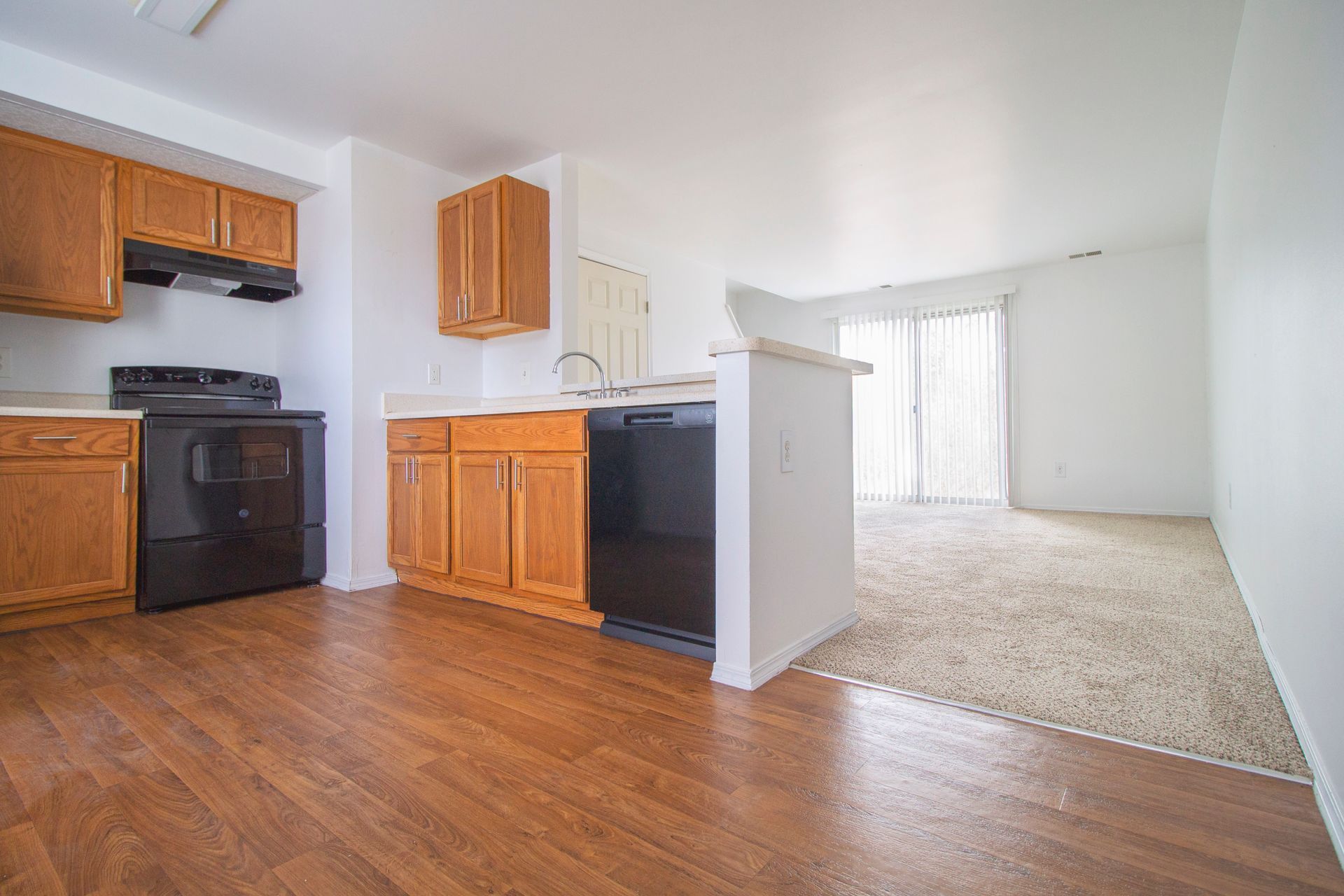 A kitchen with wooden cabinets , a black stove , and a black dishwasher.