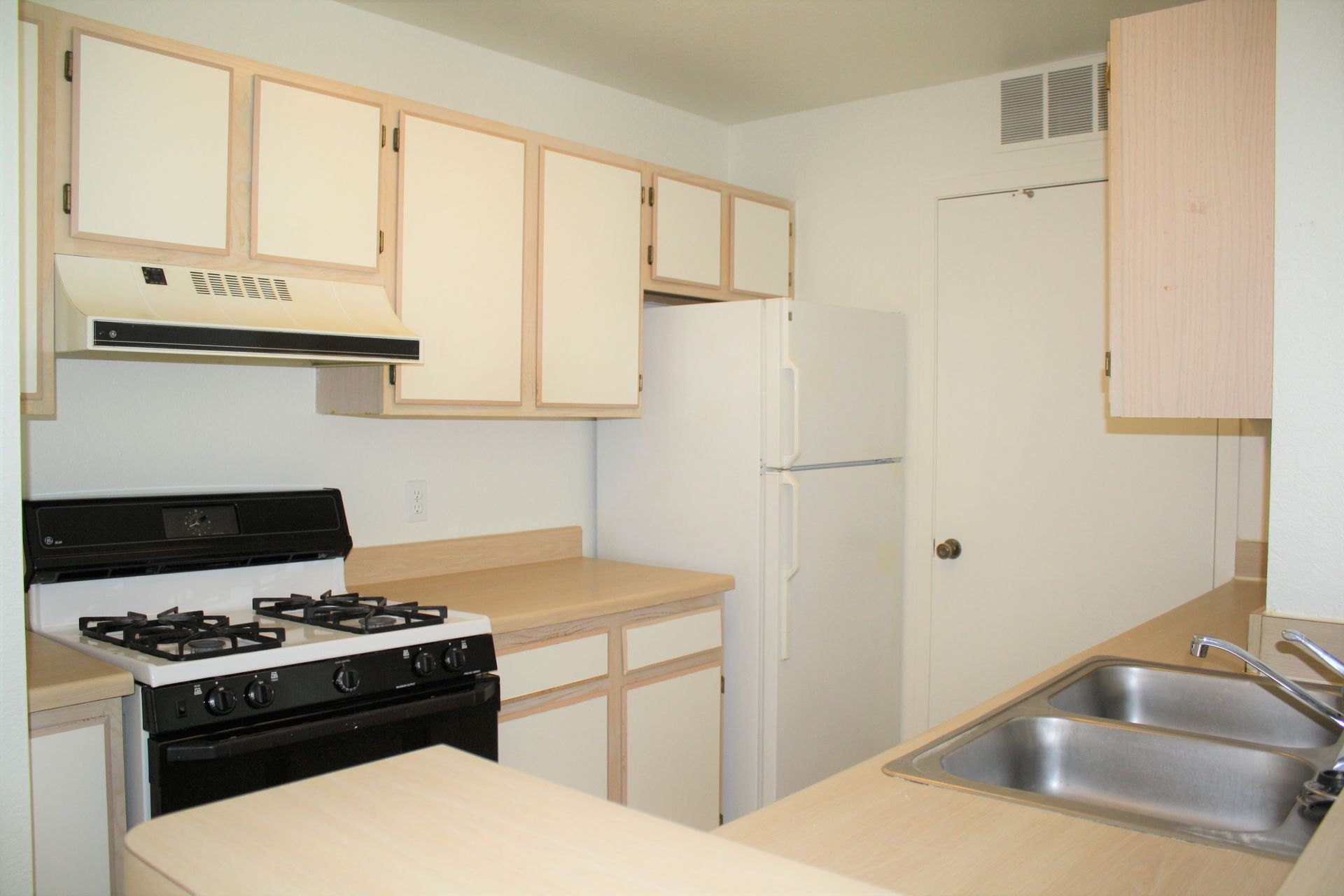 A kitchen with a stove top oven and a refrigerator