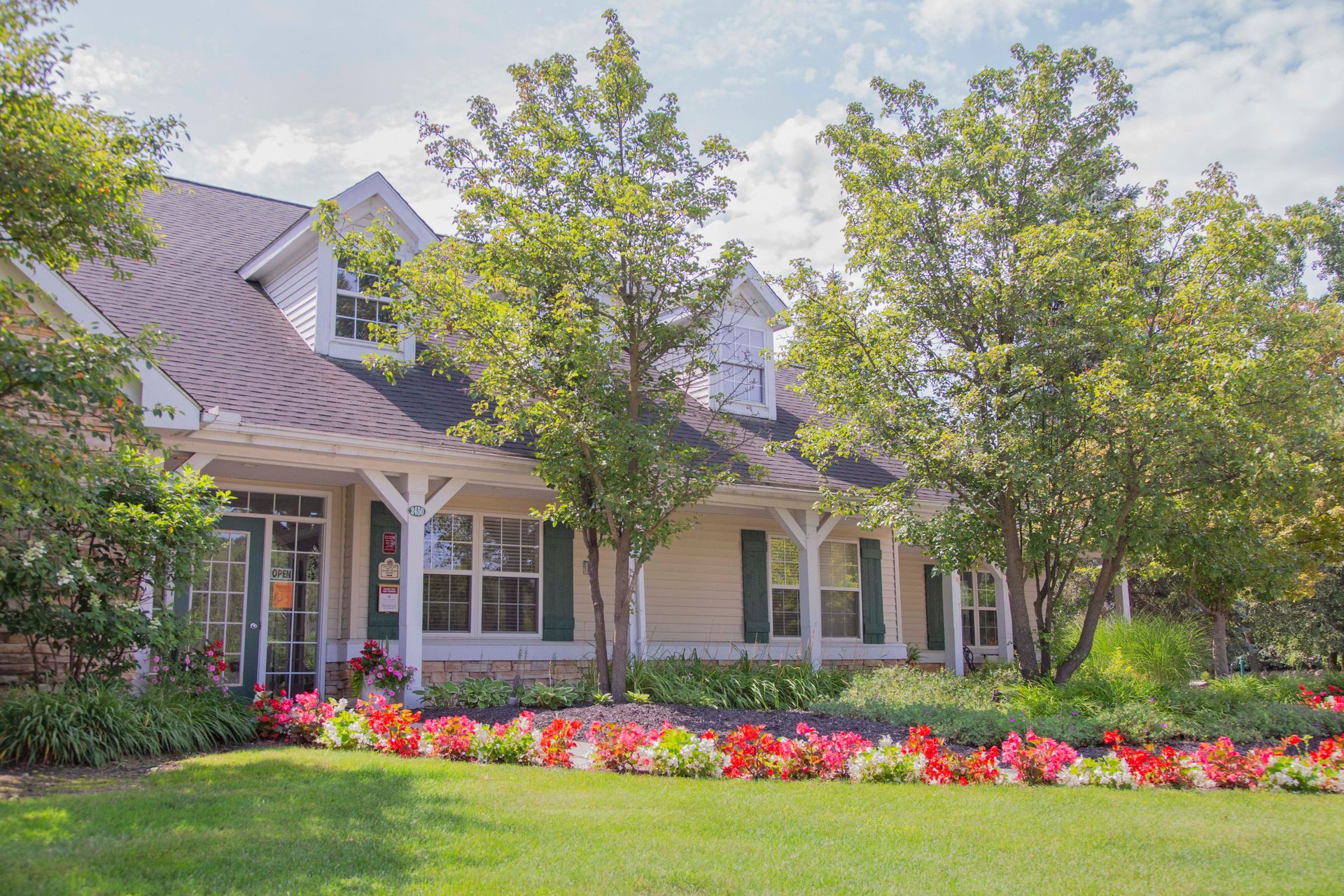 A house with a large lawn and flowers in front of it.
