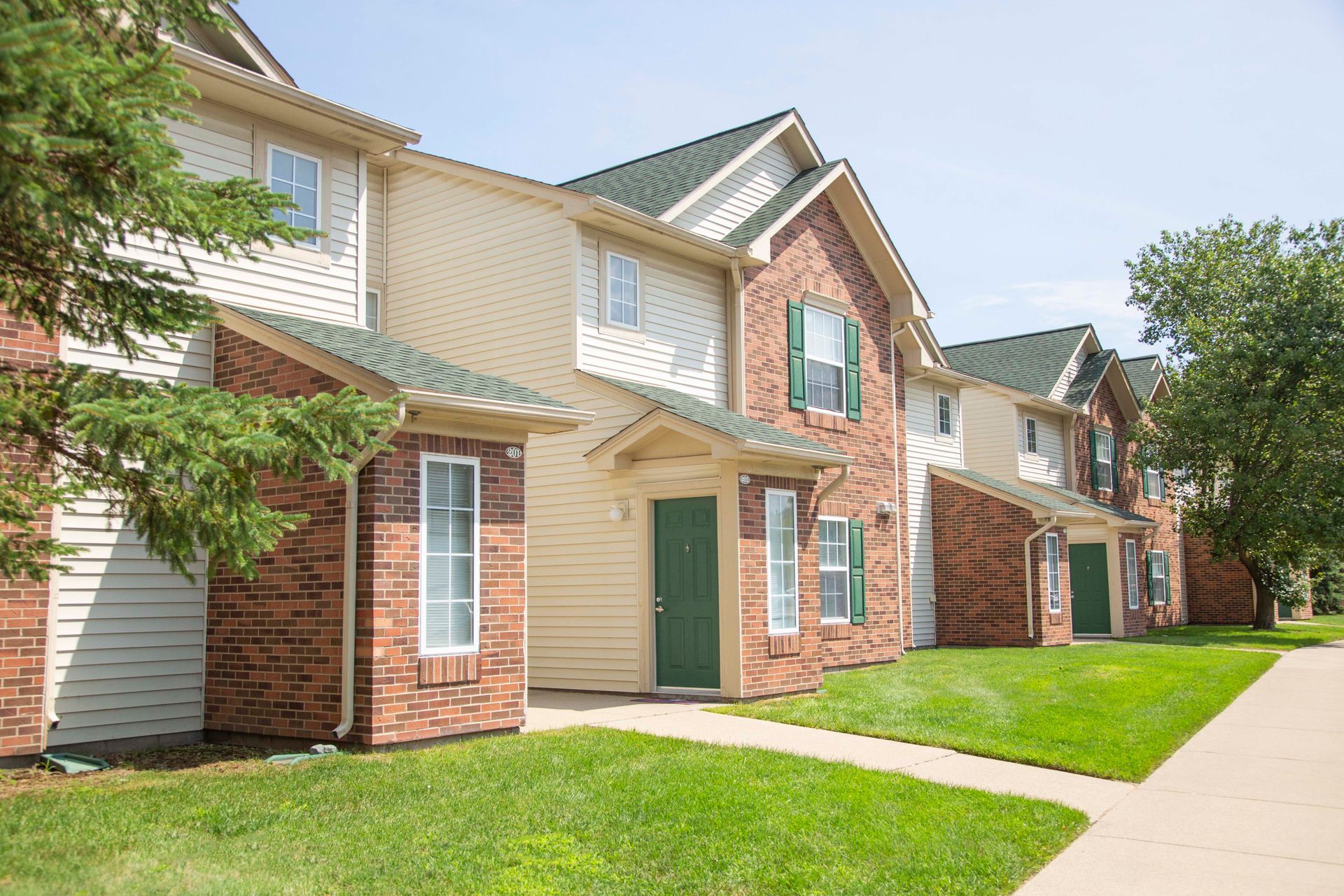 A row of apartment buildings with green shutters and white siding.