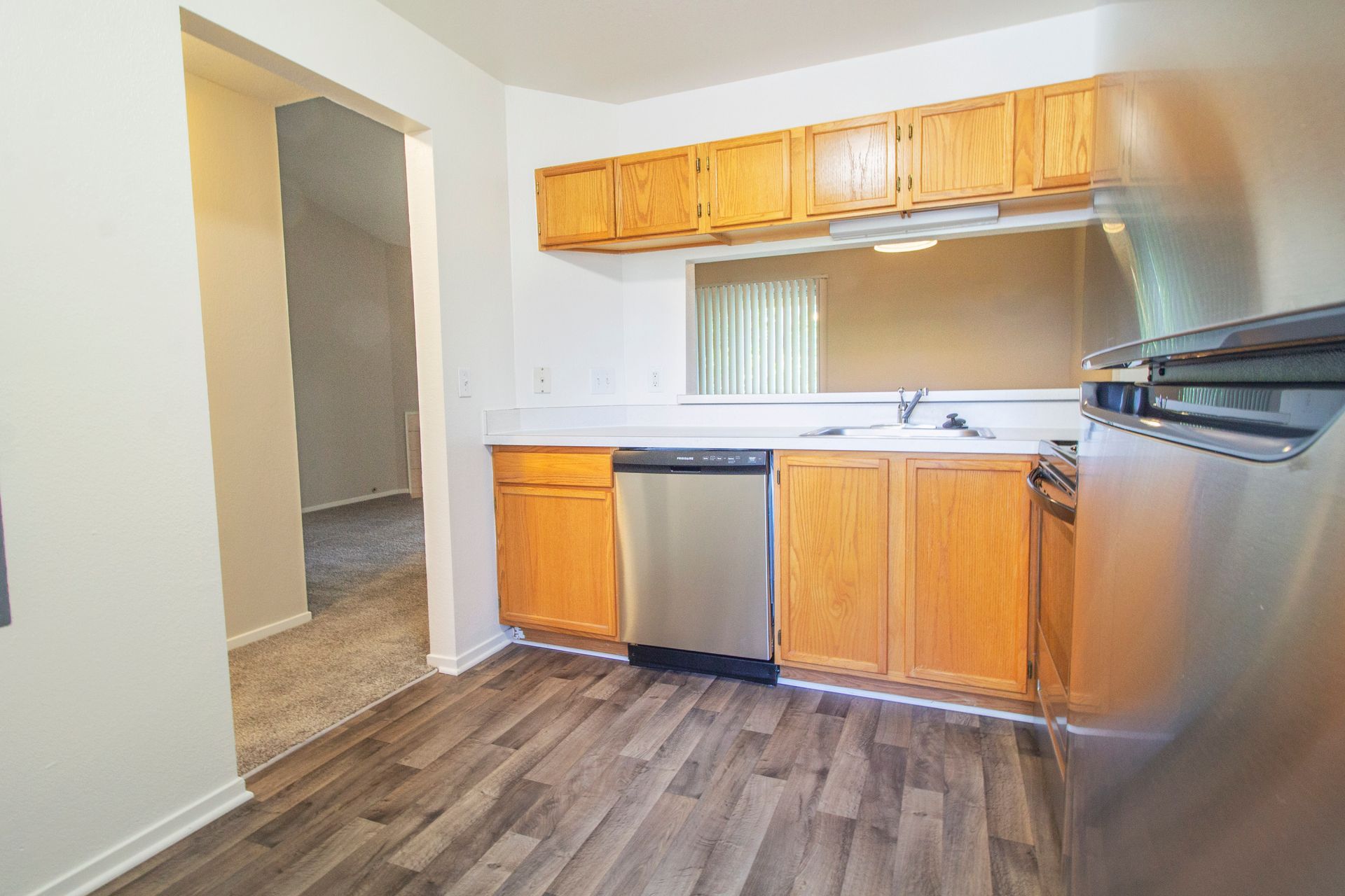 A kitchen with wooden cabinets , stainless steel appliances , a refrigerator and a dishwasher.
