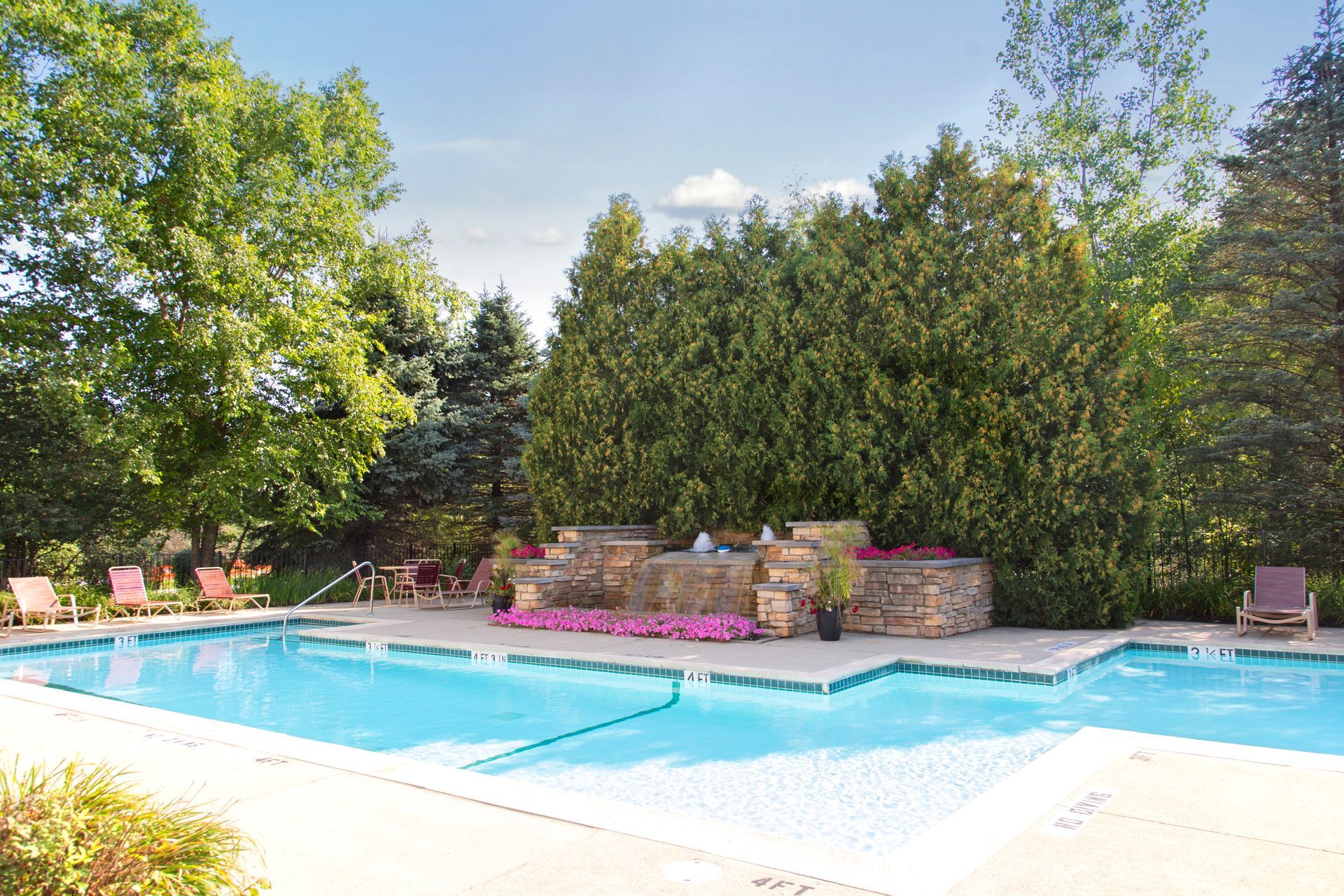 A large swimming pool surrounded by trees and chairs