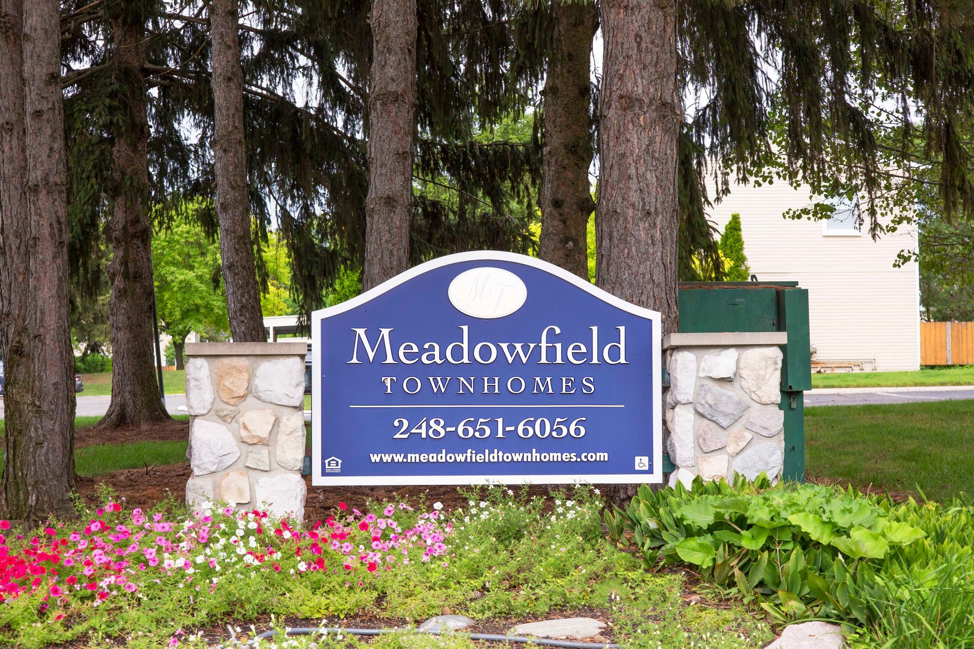 A sign for meadowfield townhomes is surrounded by trees