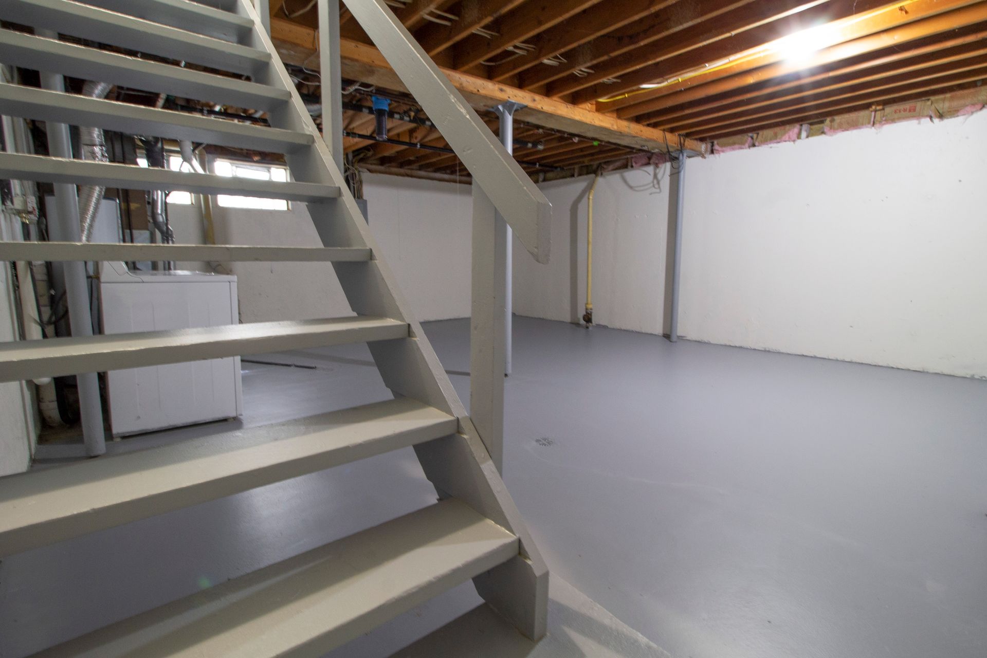 An empty basement with stairs leading up to the second floor.