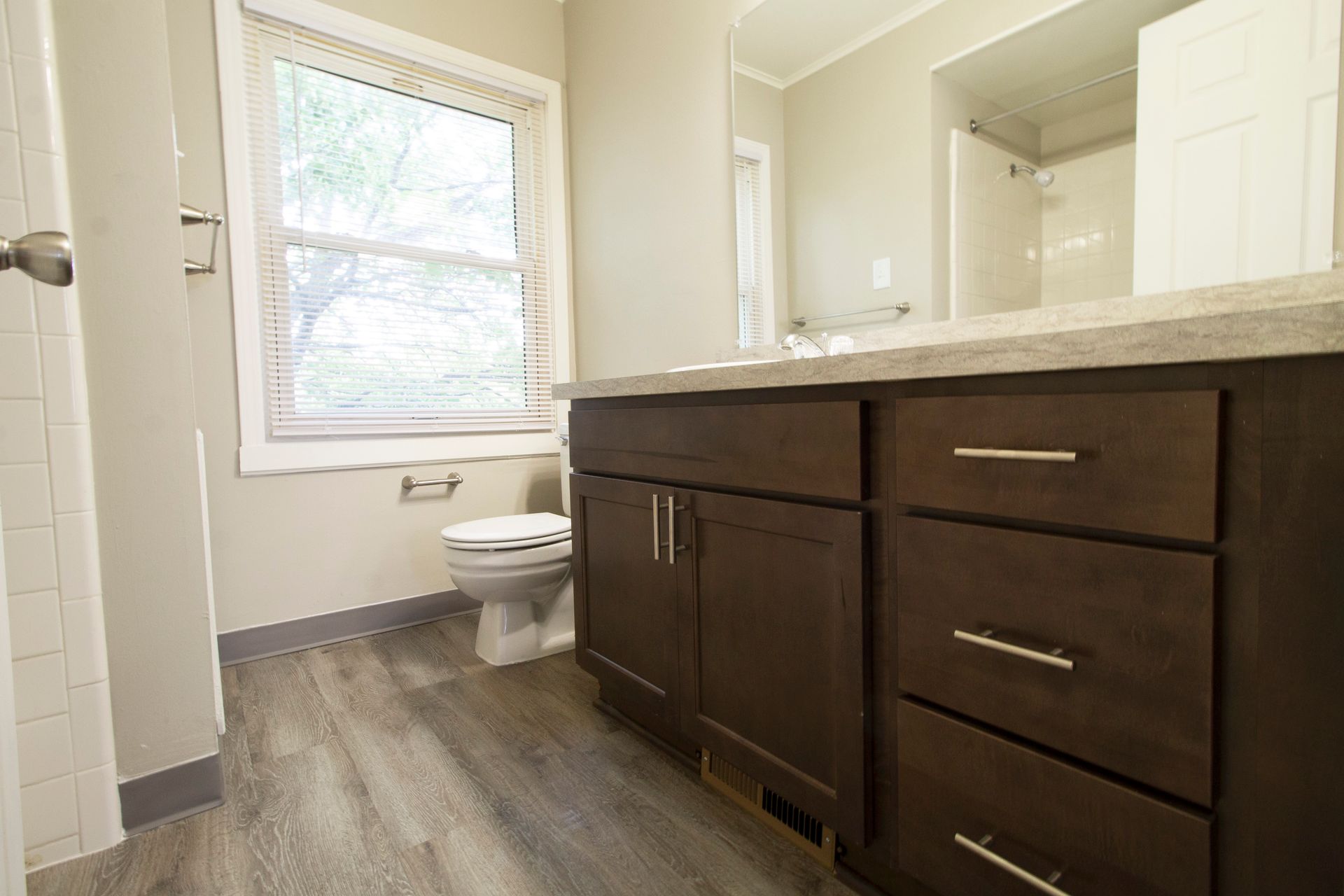 A bathroom with a toilet , sink , mirror and window.