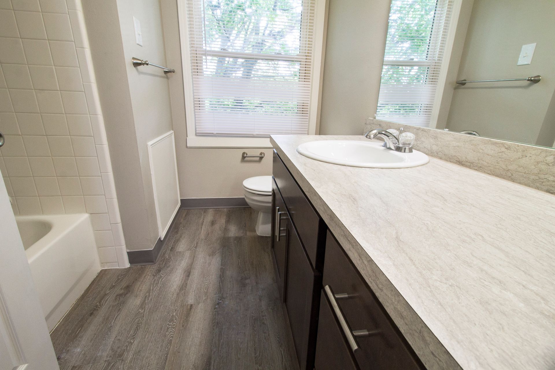 A bathroom with a sink , toilet , tub and mirror.