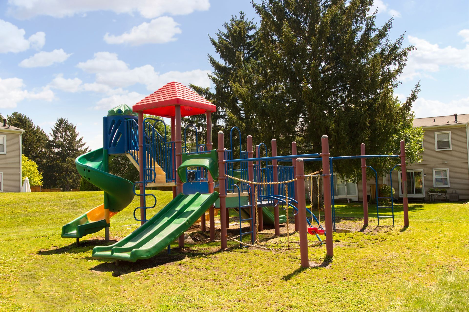 A colorful playground with a slide and swings in a grassy field.