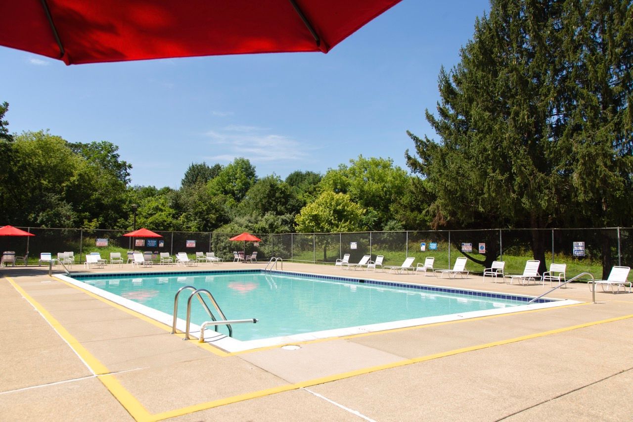 A large swimming pool with a red umbrella in the foreground