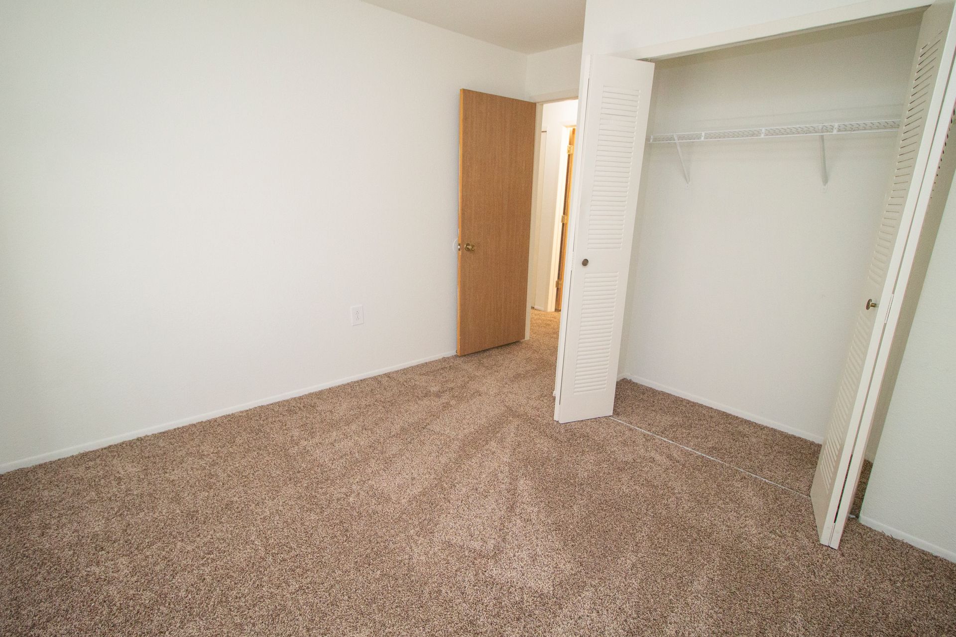 An empty bedroom with a closet and a door.