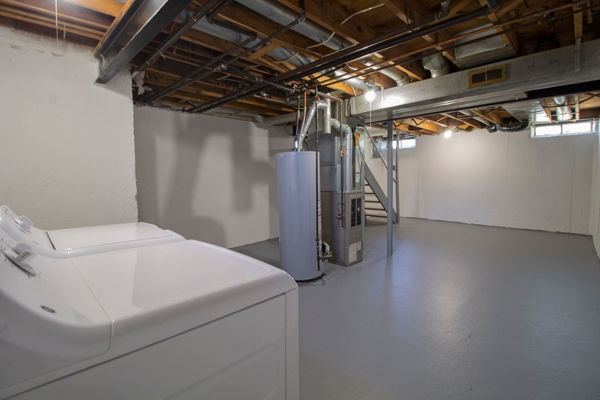 A basement with a washer and dryer and a water heater.