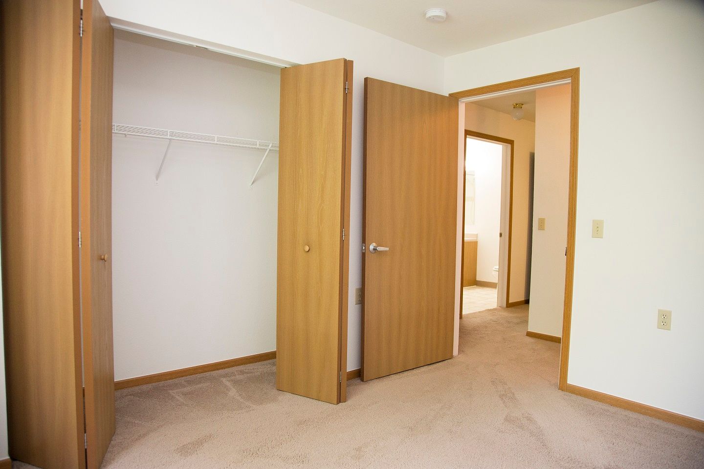 An empty bedroom with a closet and two doors open