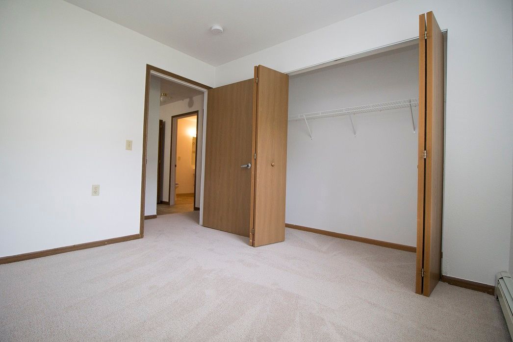 An empty bedroom with a closet and a door open