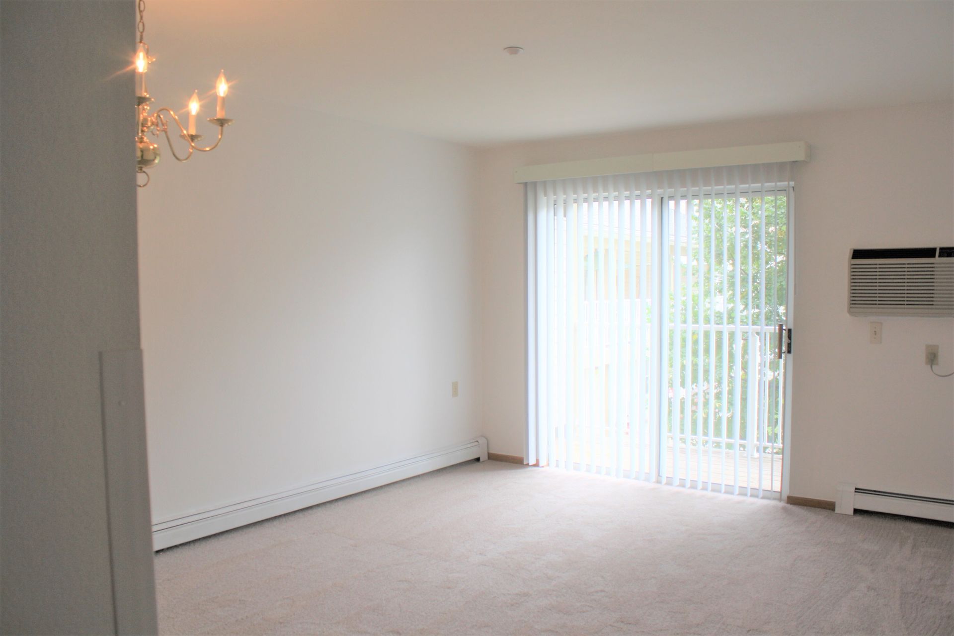 An empty living room with sliding glass doors and a chandelier