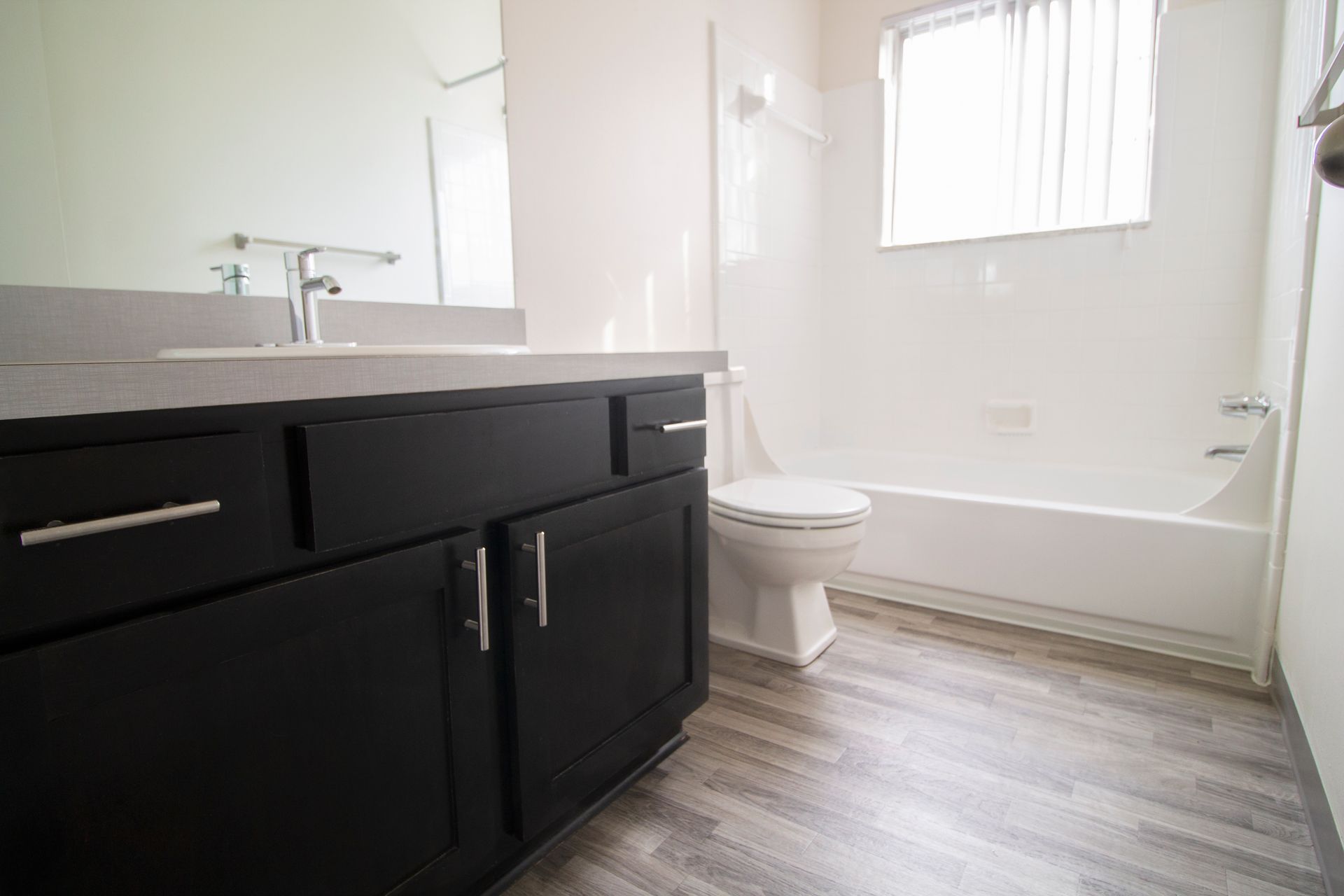 A bathroom with a sink , toilet , tub and mirror.