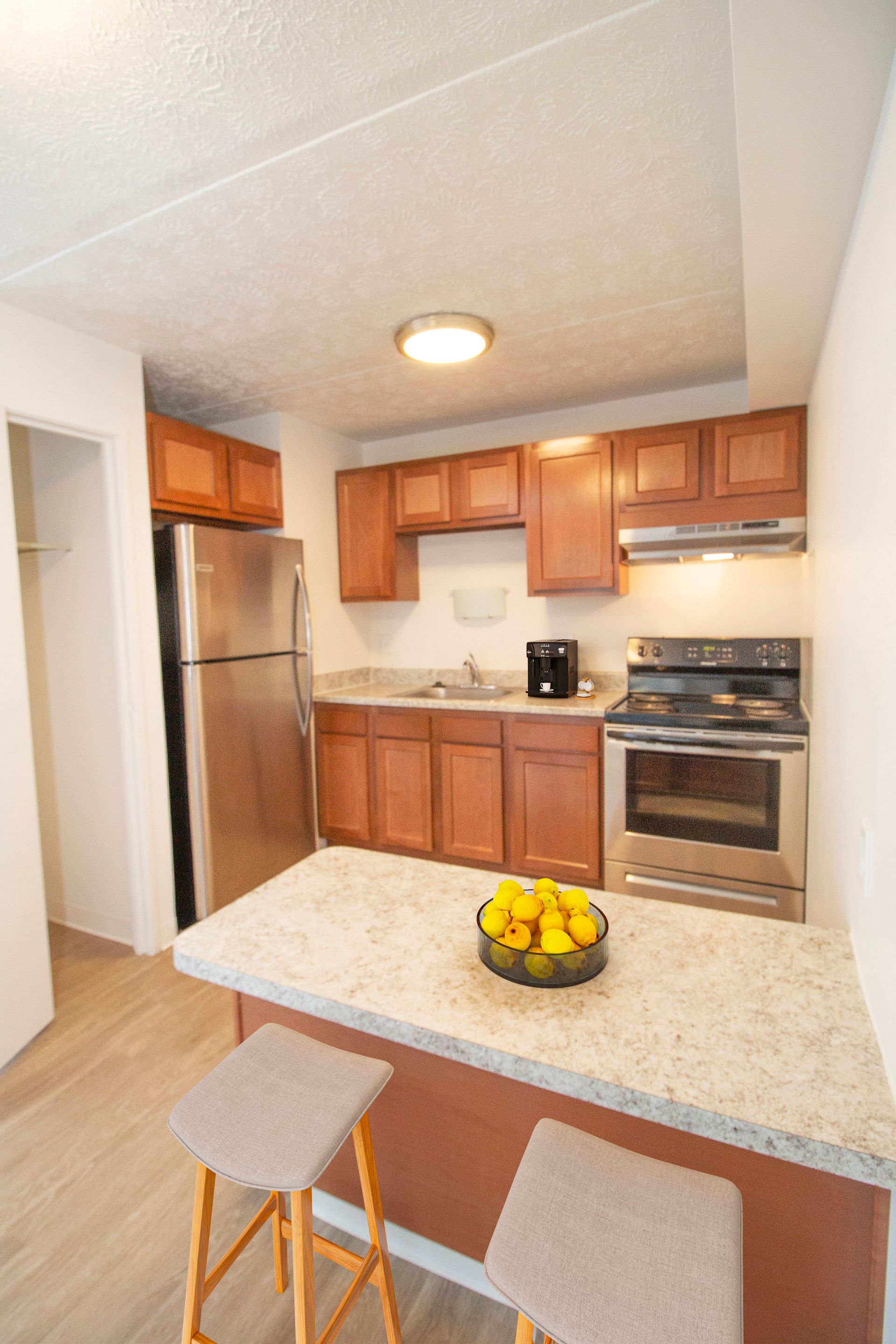 A kitchen with wooden cabinets , stainless steel appliances , a refrigerator , stove and sink.